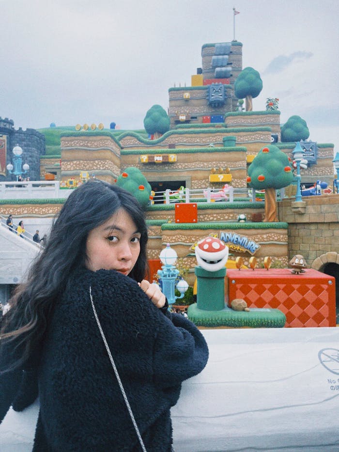 Young woman at a themed amusement park featuring vibrant, iconic game scenery.